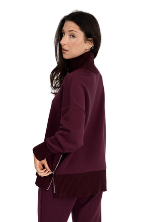 Woman wearing a burgundy sweater and pants on a white background
