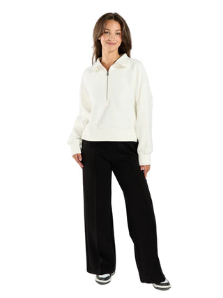 Woman wearing a white fleece jacket and black pants on a white background