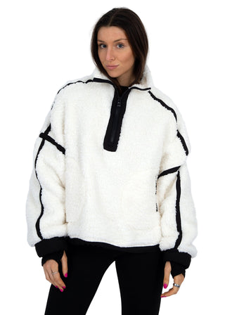 Woman wearing a white sweater with black accents against a white background