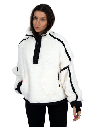 Woman wearing a white fleece jacket with black accents on a white background