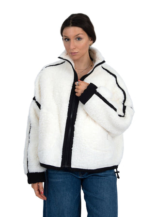 Woman wearing a white fleece jacket with black accents on a plain background