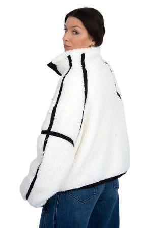 Woman wearing a white jacket with black accents on a plain background