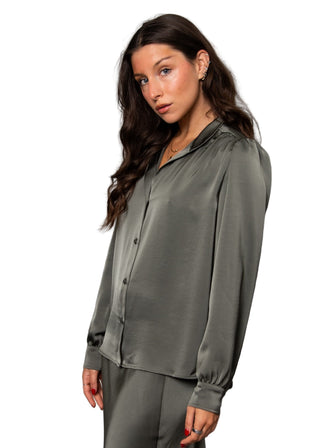 Woman wearing a green satin shirt against a gray background