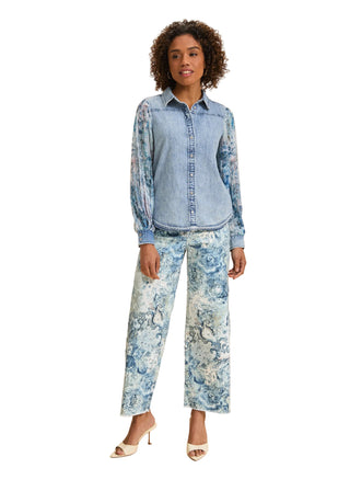 Woman wearing a denim shirt and floral pants on a beige background