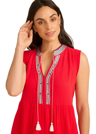 Woman wearing a red dress with intricate detailing on a beige background