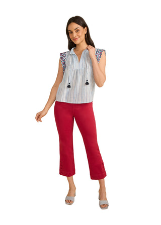Woman wearing a sleeveless striped top and red pants on a beige background