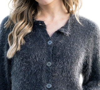 Close-up of a person wearing a textured gray cardigan with buttons.
