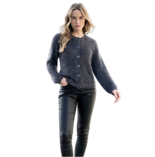 Woman wearing a dark gray sweater and black leather pants on a light background