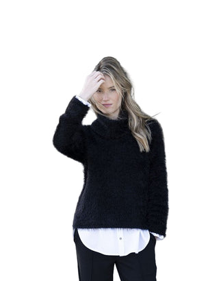 Woman wearing a black fluffy sweater over a white shirt with a blurred background
