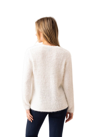 Woman wearing a white sweater and dark pants on a white background