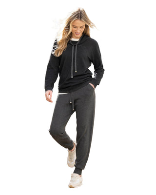 Woman in black hoodie and gray pants walking up stone steps.