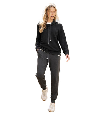 Woman in black hoodie and gray pants standing on stone steps outdoors