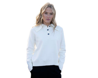 Woman wearing a white sweater with black buttons on a beach