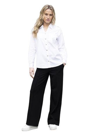 Woman wearing a white shirt and black pants standing on a cobblestone street.