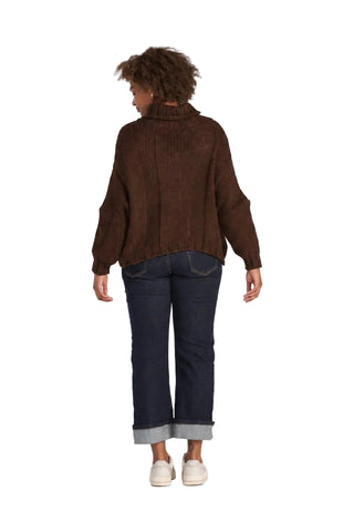 A model shown from the back wearing a brown ribbed knit mock-neck sweater, dark blue jeans with rolled cuffs, and white sneakers against a light gray studio background.