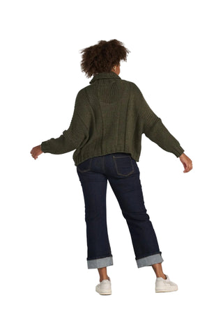 A person shown from the back wearing an olive green ribbed knit cropped sweater, dark blue jeans with rolled cuffs, and white sneakers, against a light gray studio background.