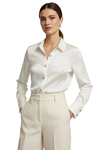 A white long-sleeve button-up shirt hanging on a hanger in a clothing store, with a hand holding the lower cuff.