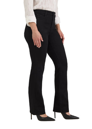 A model wearing black flared jeans, a white long-sleeve blouse, and black pointed-toe heels, shown from the waist down against a light gray studio background.