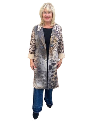 Woman wearing a patterned coat standing in front of a brick wall.