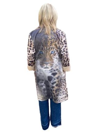 Person wearing a leopard print coat standing against a brick wall.
