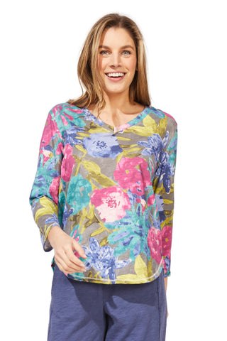 Woman wearing a colorful floral top with a plain background