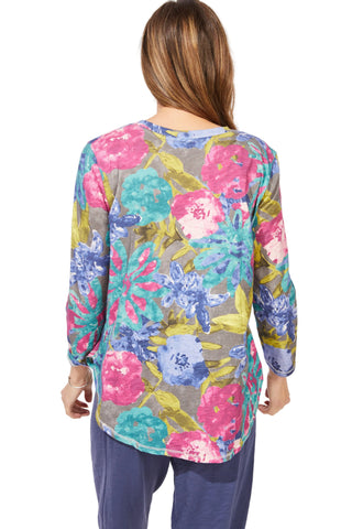 Woman wearing a colorful floral long-sleeve top against a white background