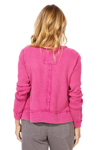 Person wearing a pink sweater with a plain background