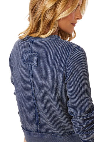 Woman wearing a blue textured sweater against a white background