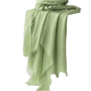 Light green scarf draped over a white surface with a blurred natural background