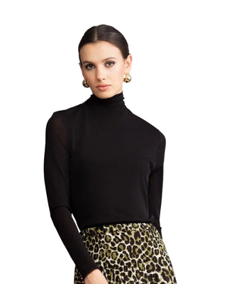 Woman wearing a black turtleneck and leopard print pants against a gray background