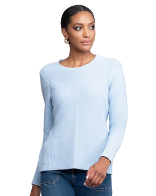 Woman wearing a light blue sweater against a gray background