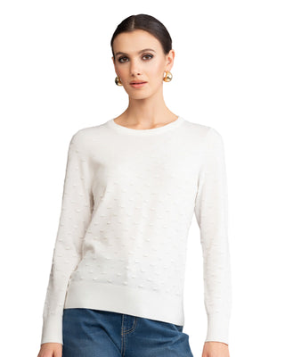Woman wearing a white sweater against a gray background