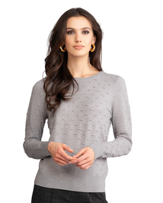 Woman wearing a gray sweater against a plain background