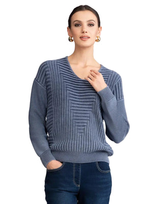 Woman wearing a blue sweater with a geometric pattern against a plain background