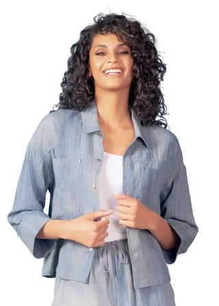 Woman wearing a light blue denim jacket over a white shirt against a light blue background