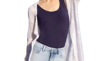 Person wearing a dark top and light cardigan on a beach