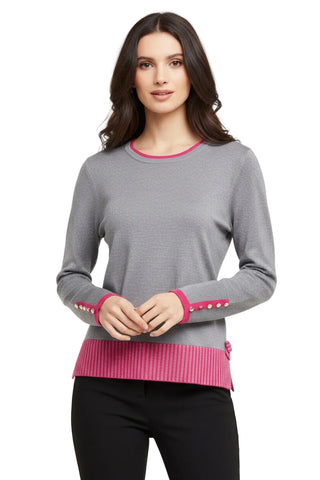 An open sewing pattern book showing a woman wearing a gray long-sleeve sweater with pink ribbed trim and pink button accents on the cuffs, alongside another page featuring matching gray pants.