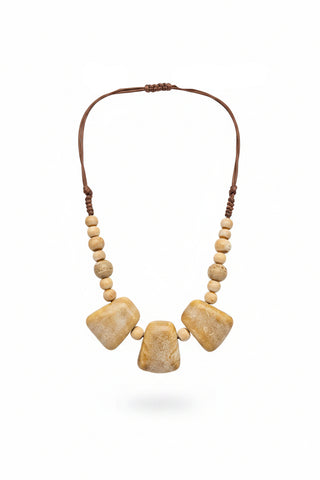 A bohemian-style statement necklace with three large polished tan stone pendants and smaller matching beads on a brown cord, displayed on a black mannequin bust.