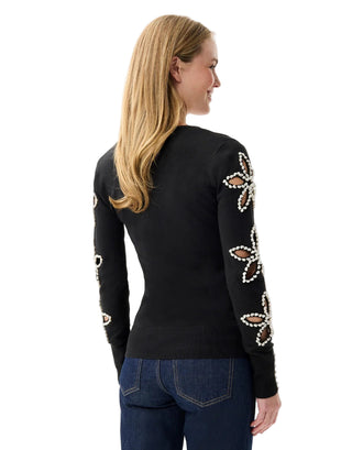 Woman wearing a black sweater with floral embellishments on a white background