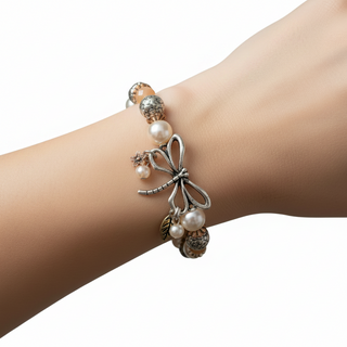 Bracelet with pearl and metal charms on a wrist against a gray background