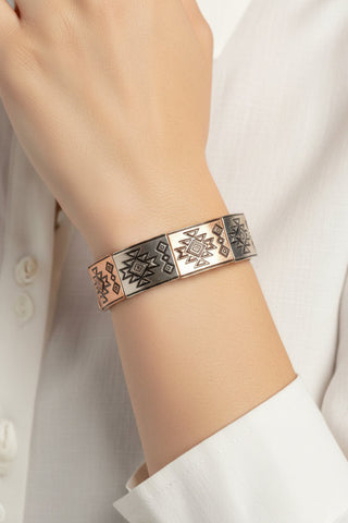 Bracelet with geometric design on a person's wrist against a white background