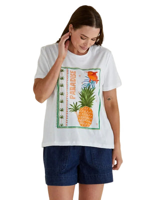Woman wearing a white t-shirt with a pineapple graphic on a beige background