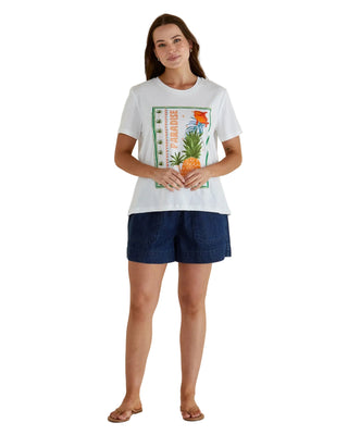 Woman wearing a white t-shirt with a graphic design and dark shorts on a beige background