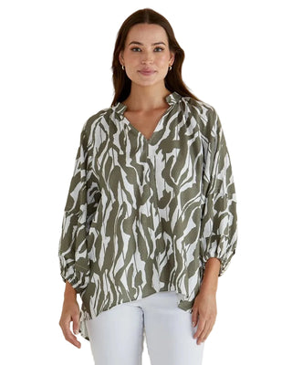 Woman wearing a green and white patterned blouse against a beige background