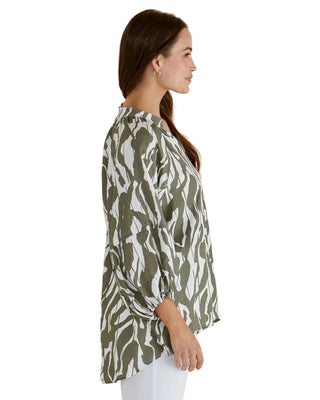 Woman wearing a green and white patterned blouse against a beige background