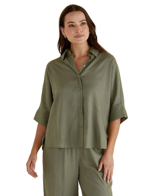 Woman wearing a green shirt and pants against a beige background