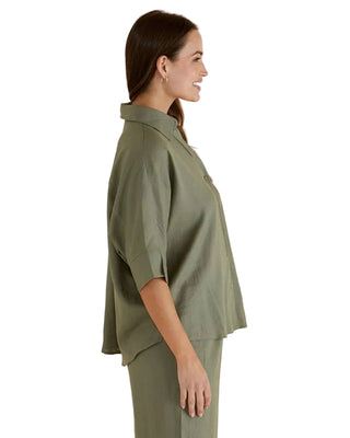 Woman wearing a green outfit against a beige background