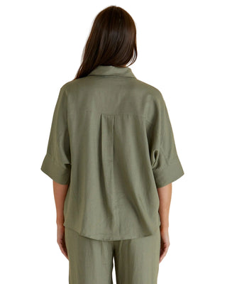 Person wearing a green shirt and pants on a beige background