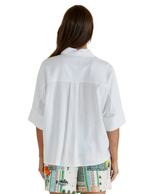 Woman wearing a white shirt with a colorful patterned skirt on a beige background