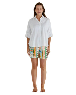 Woman wearing a white shirt and colorful shorts on a beige background